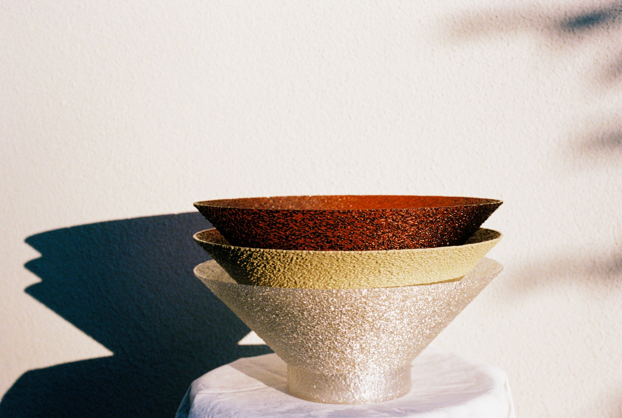 Three stacked ceramic bowls in sunlight.