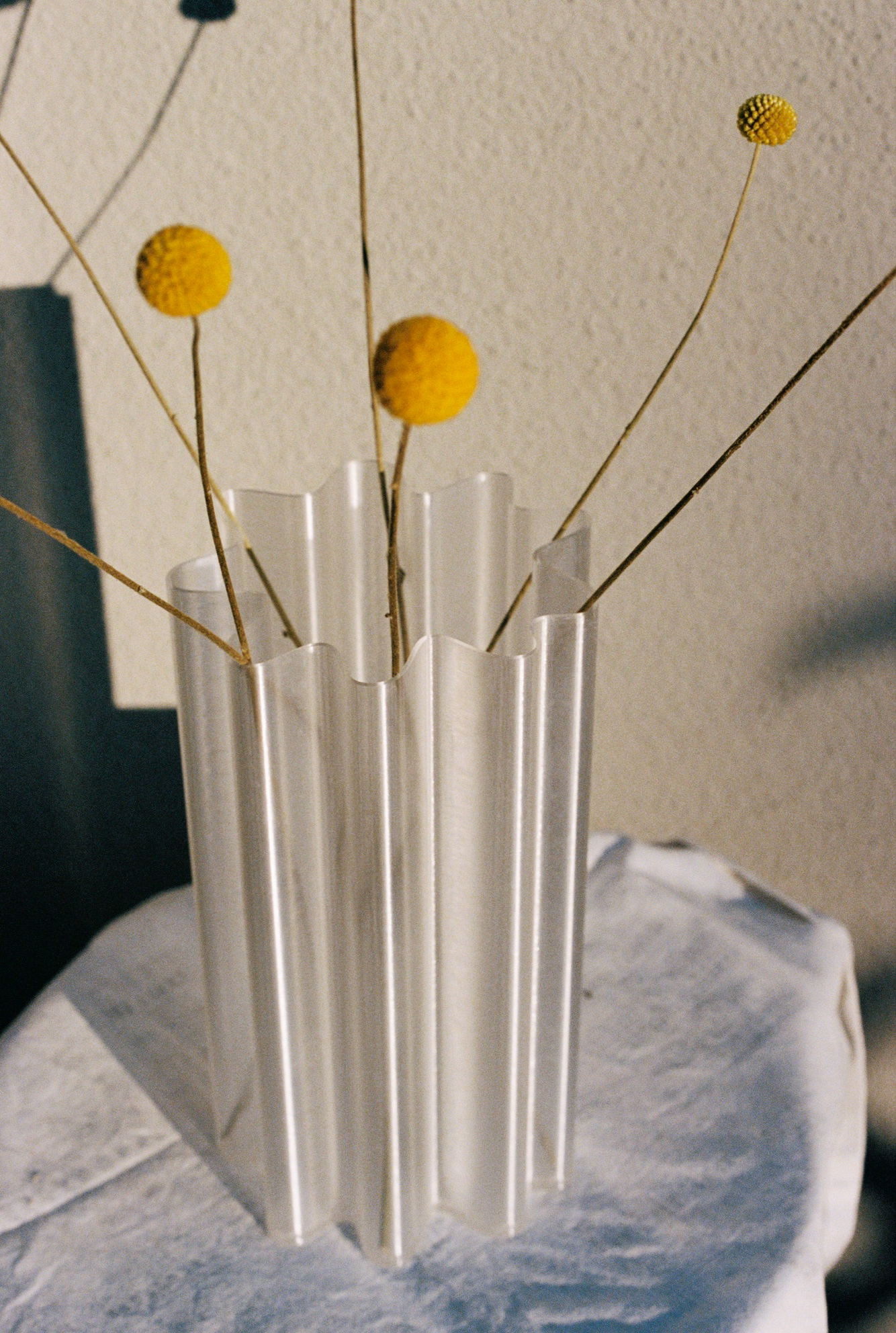 Tall fluted vase with dried yellow flowers.
